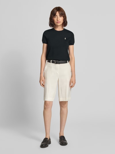 Modelka nosi jednokolorowy Slim Fit Strickshirt aus Baumwoll-Mix von Polo Ralph Lauren, drobny splot, wyhaftowane logo, okrągły dekolt, krótki rękaw, prążkowane wykończenia, mieszanka bawełny, całkowity widok z przodu.