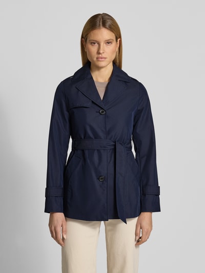 Kobiece modelka nosi Regular Fit Trenchcoat aus Baumwoll-Mix od s.Oliver RED LABEL, efekt: jednolity kolor, splot twill, hydrofobowy, krój regular fit, kołnierz z połami, listwa guzikowa, pasek w talii, długość: krój krótki, aplikacja z metką, pas na plecach, pagony, długo rękaw, patki przy mankietach, kieszeń wewnętrzna, wpuszczane kieszenie, mieszanka bawełny; widok całej sylwetki z przodu.