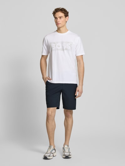 Männermodel trägt Regular Fit Shorts mit elastischem Bund Modell 'S_SPEEDFLEX' von BOSS Green in Unifarben mit Label Print, Ganzkörperansicht von vorne.
