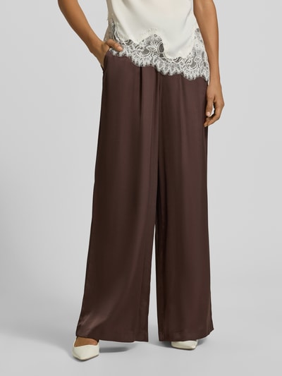 Frauenmodel trägt Wide Fit Stoffhose mit Viskose-Anteil von comma in Braun, elastischer Bund, Satin-Optik, Nahaufnahme Unterkörper.
