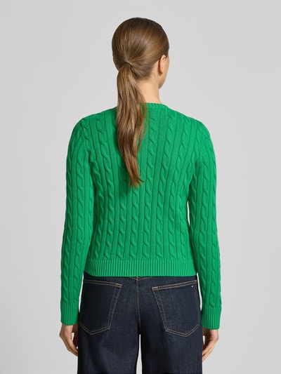 Frauenmodel trägt grüne Strickjacke mit Zopfmuster und Label-Stitching Modell 'RALHAN' von Lauren Ralph Lauren, Slim Fit, Rückansicht.