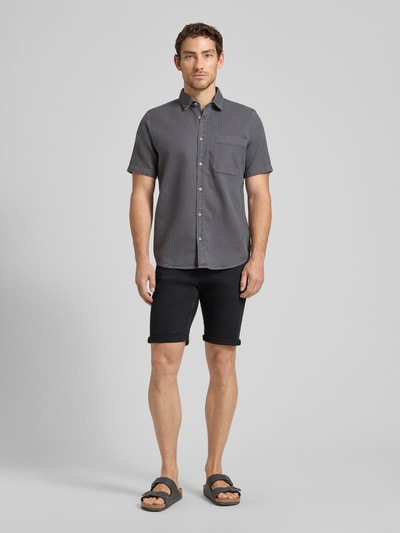 Mannelijk model draagt Regular Fit Jeans Bermudas uit katoenmix van Tom Tailor, denimlook, regular fit, slim leg, 5-pocket, knoopsluiting, label patch, riemlussen, kleur zwart, textuur glad, detailopname volledige voorkant.