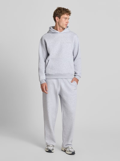 Männermodel trägt Regular Fit Hoodie aus Baumwoll-Mix von REVIEW in Grau mit Känguru-Tasche, Kapuze, elastischen Abschlüssen, Ganzkörperansicht von vorne.