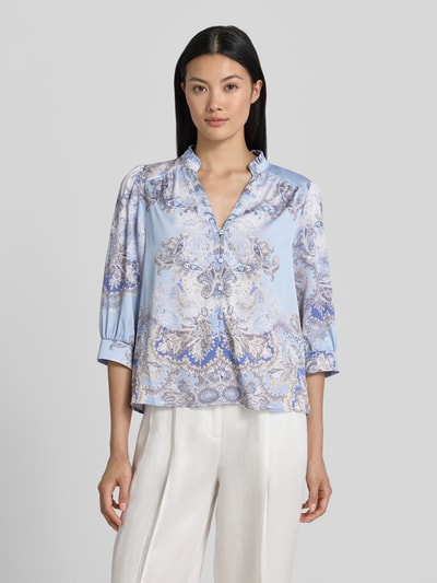 Frauenmodel trägt Regular-Fit Damen Bluse mit Allover-Look und 3/4-Arm Modell 'Roselle Artist Paisley' von Neo Noir, Ganzkörperansicht von vorne. Rückenlänge bei Größe 36: 57 cm, Ärmellänge: 43 cm, Stehkragen, V-Ausschnitt, Knopfleiste, Farben in Blau und Creme mit feinem Paisley-Muster.