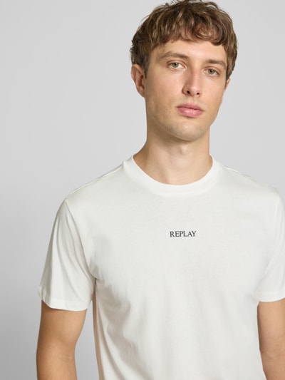 Männermodel trägt T-Shirt mit Rundhalsausschnitt und Logo von Replay, reine Baumwolle, Slim Fit, Nahaufnahme Oberkörper.
