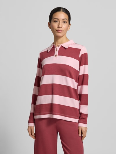 Frauenmodel trägt Sweatshirt mit Polokragen Modell 'BARNI' von Soyaconcept, breite rosa und bordeauxrote Streifen, lockerer Schnitt, Material-Mix mit Modal-Anteil, kurze Knopfleiste, Ganzkörperansicht von vorne.