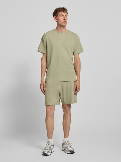 Männermodel trägt Shorts mit Strukturmuster und Label-Stitching von BLKVIS aus Reine Baumwolle, Regular-Fit in hellem Grün, Ganzkörperansicht von vorne.