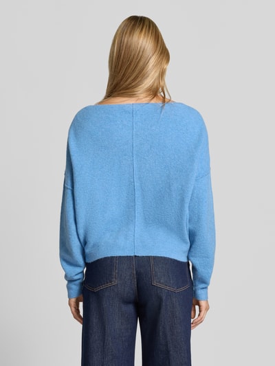 Frauenmodel trägt Relaxed Fit Strickpullover aus Material-Mix mit Leinen-Anteil von American Vintage in Hellblau, gerippte Abschlüsse, überschnittene Schultern, langärmlig, Rundhalsausschnitt, Rückenlänge 50 cm, Ärmellänge 60 cm, Ganzkörperansicht Rückansicht.