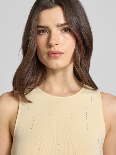 Frauenmodel trägt Slim Fit Top aus Viskose-Mix mit Strick-Optik Modell 'Saya' von Gestuz, Strasssteinbesatz, Rundhalsausschnitt, Ärmelloses-Design, feine Rippstruktur, cremefarben, Nahaufnahme Oberkörper. Rückenlänge bei Größe S: 52 cm.