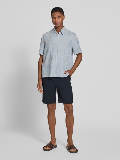 Męski model nosi Shorts mit elastischem Bund Modell 'Samos' od Casual Friday, krój regular fit, materiał z domieszką wiskozy, szerokość w rozmiarze M: 40 cm, długość nogawki wewnętrznej: 21 cm, widok całej sylwetki z przodu.