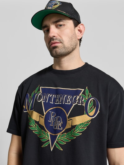 Männermodel trägt Regular Fit T-Shirt mit Logo-Print von RHUDE aus reiner Baumwolle, schwarz mit Rundhalsausschnitt, Nahaufnahme Oberkörper.