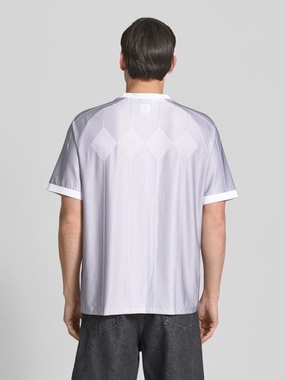 Männermodel trägt Regular Fit T-Shirt mit Label Print Modell 'DWILD' von HUGO, gestreiftes Allover-Muster, V-Ausschnitt, Ganzkörperansicht Rückansicht