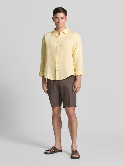 Männermodel trägt Regular Fit Leinenhemd mit Kentkragen von GAP in Gelb, reine Leinenstruktur, Knopfleiste, Ganzkörperansicht von vorne. Rückenlänge 71 cm, Schulterbreite 49 cm, Ärmellänge 64 cm bei Größe M.