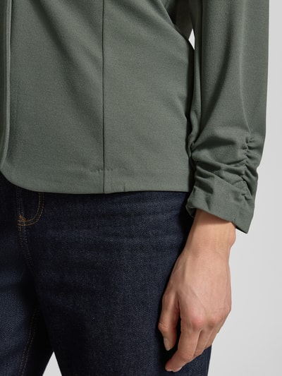 Kobieta nosi Blazer mit Raffungen Modell 'Siham' od Soyaconcept, elastyczna mieszanka materiałów, krój slim fit, marszczenia, kolor oliwkowy, zbliżenie na rękaw, detal.