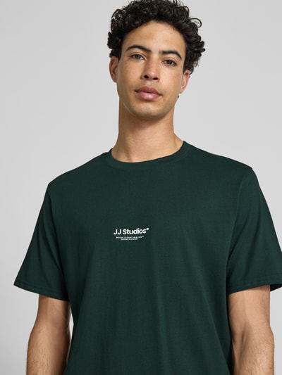 Männermodel trägt Regular Fit T-Shirt mit Logo-Print Modell 'Soho' von Jack & Jones aus grüner Baumwolle, Nahaufnahme Oberkörper.