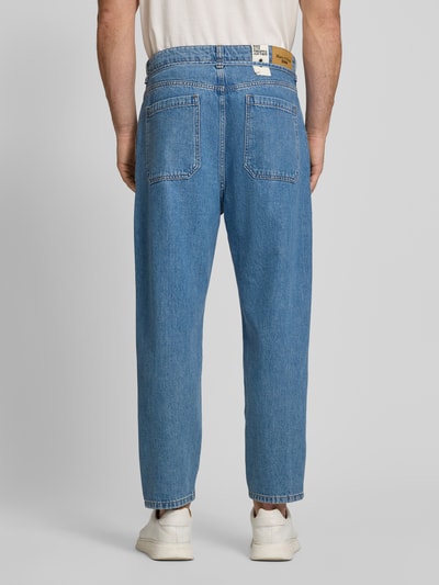 Männermodel trägt Wide Leg Tapered Fit Jeans aus Baumwoll-Ananas-Faser-Mix Modell 'ISAK' von Marc O'Polo Denim in Denim-Optik, Label-Patch, Nieten, Kontrast-Nähte, Bindegürtel, Gesäßtaschen, Ganzkörperansicht Rückansicht.