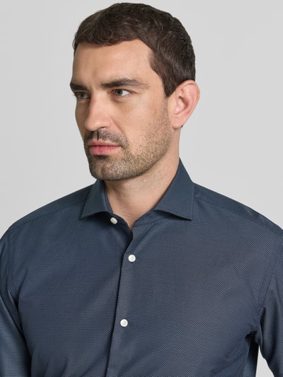 Männermodel trägt Regular Fit Businesshemd aus reiner Baumwolle Modell 'H-JOE-SP' von BOSS in Dunkelblau mit feiner Struktur, Nahaufnahme Oberkörper. Herren Businesshemd von BOSS.