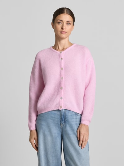 Frauenmodel trägt Strickjacke mit Woll-Anteil Modell 'VITOW' von American Vintage in Rosa, lockere Passform, Ganzkörperansicht von vorne. Damen Strickjacke, elastischer Material-Mix, Rundhalsausschnitt, Knopfleiste, gerippte Abschlüsse, Rückenlänge 55 cm, Ärmellänge 64 cm.