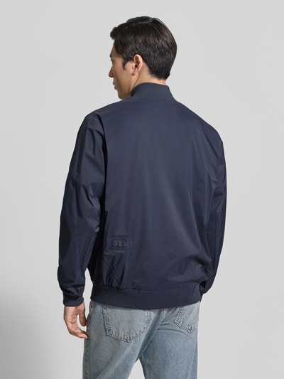 Männermodel trägt dunkelblauen Blouson mit Label-Detail Modell 'MILD' von GOFRANCK, Gerader-Schnitt, Stehkragen, Gerippte-Abschlüsse, Rückenansicht Ganzkörperansicht Rückansicht. Rückenlänge bei Größe M: 70 cm, Schulterbreite: 45 cm, Brustweite: 63 cm, Ärmellänge: 71 cm.
