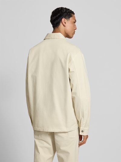 Männermodel trägt Relaxed Fit Jacke in Denim-Optik von Forét aus Reine Baumwolle, cremefarben, Rückenansicht, Ganzkörperansicht Rückansicht. Rückenlänge 74 cm, Schulterbreite 51 cm, Ärmellänge 67 cm, Kentkragen, AufgesetzteTaschen, Größe M.