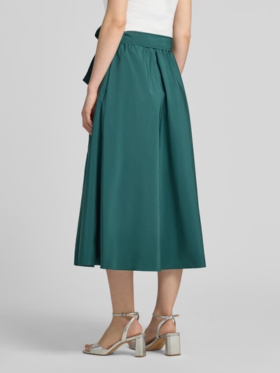 Frauenmodel trägt Ausgestellter Midi-Rock mit Baumwoll-Anteil Modell 'ALPACA' von Weekend Max Mara in Dunkelgrün, glatte Textur, Ganzkörperansicht Rückansicht. Damen Midi-Rock von Max Mara.