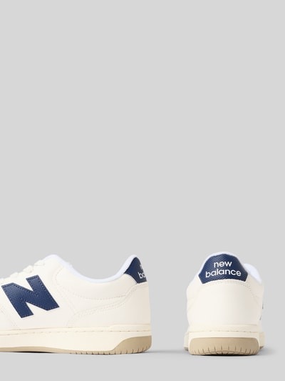 Produktfoto, Sneaker mit Label-Details Modell '550' von New Balance, cremefarbene Oberfläche, blaue Akzente, abgerundete Spitze, sichtbare Schnürung, Sohlenhöhe etwa 3 cm, Kontext: Herren Sneaker, Schafthöhe ca. 8 cm, Schaftweite ca. 10 cm, strukturierte Textur, neutrale Farbtöne