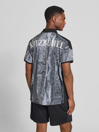 Männermodel trägt Regular Fit T-Shirt mit V-Ausschnitt von COLUCCI, grau-schwarze Muster, Motiv-Patch und Logo-Print, Ganzkörperansicht Rückansicht.
