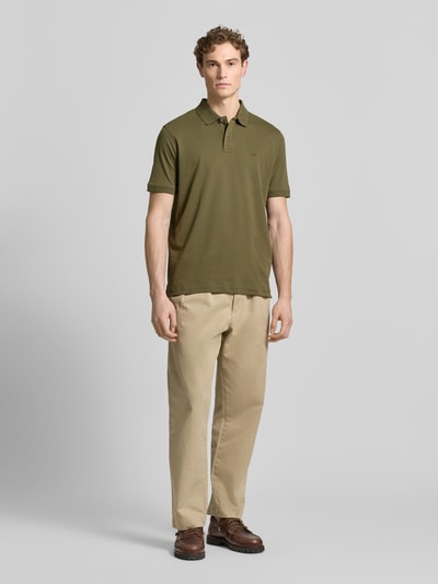 Männermodel trägt Regular Fit Poloshirt mit Logo-Stitching von Fynch-Hatton in Olivgrün, Baumwolle, Ganzkörperansicht von vorne.