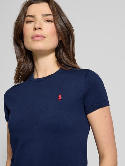 Frauenmodel trägt Regular Fit Kurzarmpullover aus Baumwoll-Mix von Polo Ralph Lauren in Dunkelblau mit rotem Logo-Stitching, Nahaufnahme Oberkörper.