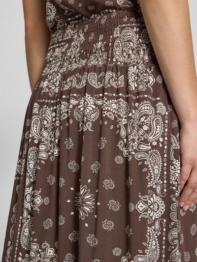Vrouwenmodel draagt Ausgestellter maxi-rok uit pure viscose model 'SAKI AMBEL' van Only in bruin met witte paisleyprint, detailopname heup.