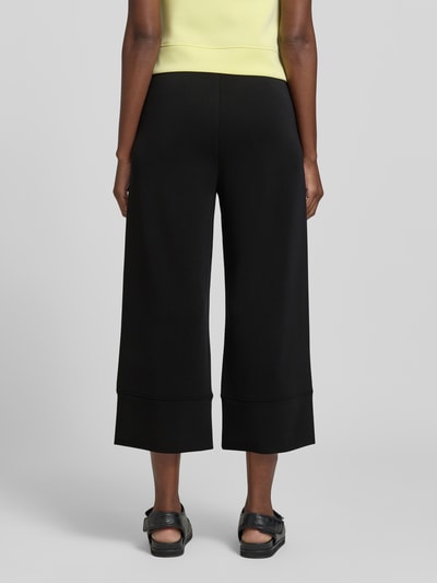 Frauenmodel trägt Regular Fit Culotte aus Modal-Mix von s.Oliver RED LABEL in Schwarz mit elastischem Bund und weitem Bein, Ganzkörperansicht Rückansicht.
