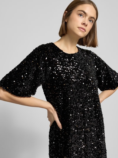 Kobiece model prezentuje sukienkę koktajlową z cekinowym obszyciem Model 'KAM' od Pieces, efekt: jednolity kolor, efekt błyszczący, krój wąski, długość mini, dekolt w łódkę, wyhaftowane logo, krótki rękaw, prosty dół, wykończenie materiału: aksamit; ujęcie: z przodu, zbliżenie na górną część ciała.