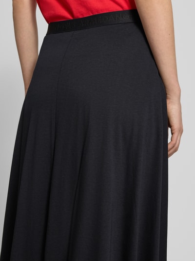 Vrouwenmodel draagt Loose Fit midi-rok uit lyocell-baumwoll-mix model 'ILENIAA LARAA' van Armedangels, look: effen, elastische band met logostitching, fijnrib materiaalverwerking, damesrok met midilengte, detailopname rugaanzicht.
