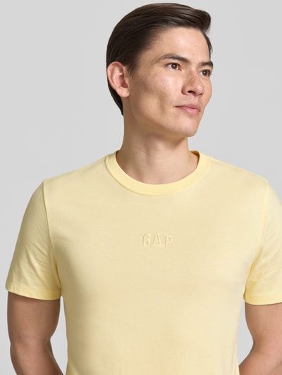 Männermodel trägt T-Shirt mit Rundhalsausschnitt und Label-Stitching von GAP in Hellgelb, reine Baumwolle, Regular Fit, Nahaufnahme Oberkörper.