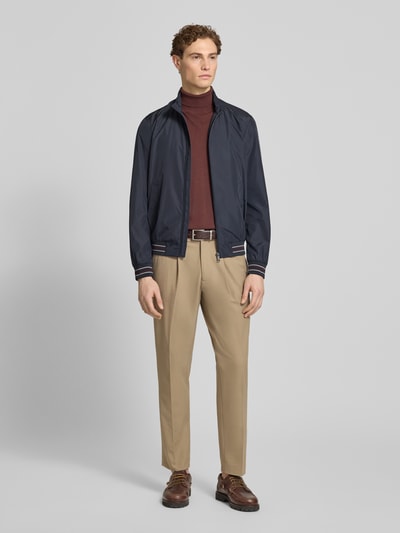 Męski model nosi Blouson mit Stehkragen und Reißverschluss od Geox, kolor granatowy, krój regular fit, widok całej sylwetki z przodu, długość tyłu 68 cm, szerokość ramion 46 cm, szerokość klatki piersiowej 56 cm, długość rękawa 68 cm