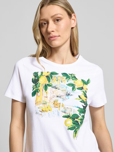 Vrouwenmodel draagt T-shirt met motiefprint en ronde hals van Marc Cain in puur katoen, straight fit, ruglengte maat 36: 54 cm, close-up bovenlichaam.