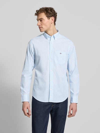 Männermodel trägt Slim Fit Freizeithemd mit Brusttasche von Gant in Hellblau-Weiß gestreift, reine Baumwolle, Button-Down-Kragen, Ganzkörperansicht von vorne.