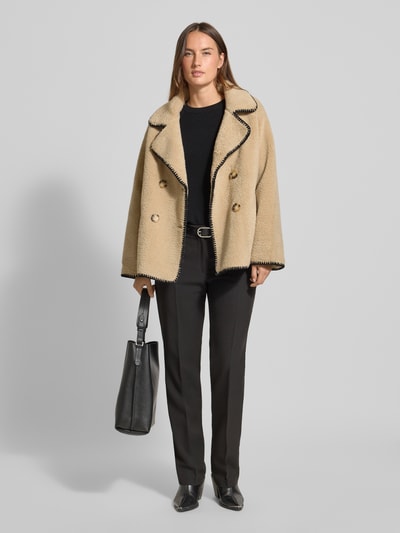 Frauenmodel trägt Jacke aus Teddyfell mit Eingrifftaschen von Apricot, relaxed Fit, zweireihig, beige mit schwarzem Reverskragen, Ganzkörperansicht von vorne.