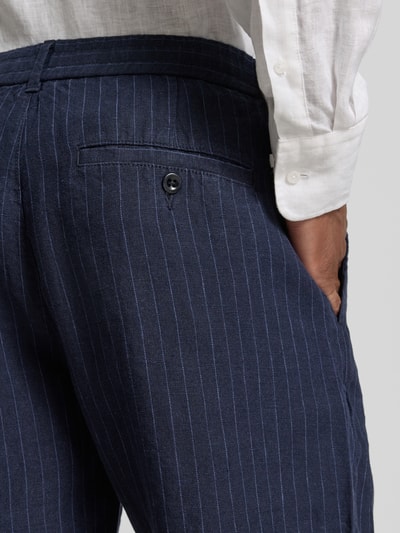 Männermodel trägt Straight Fit Leinenshorts mit Gesäßtaschen von Gant aus Reine Leinen in Dunkelblau mit feinen Streifen, Detailaufnahme. Bundweite in Größe M 43 cm, Innenbeinlänge 23 cm, Elastischer Bund mit Tunnelzug.