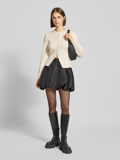 Frauenmodel trägt Loose Fit Strickjacke mit Woll-Anteil von Gina Tricot im Material-Mix, Rundhalsausschnitt, Knopfleiste, Ganzkörperansicht von vorne.