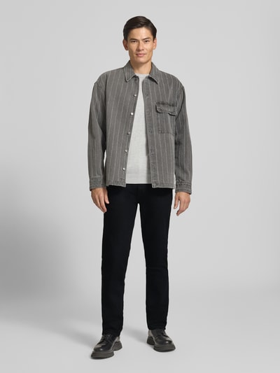 Männermodel trägt Straight Fit Jeans aus Baumwoll-Mix von Lee, schwarze Farbe, glatte Struktur, Ganzkörperansicht von vorne.