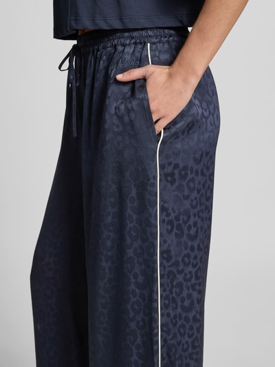 Frauenmodel trägt Wide Fit Sweatpants mit Viskose-Anteil von Lala Berlin, dunkelblauer Animal-Print, elastischer Bund, Eingrifftaschen, Nahaufnahme Oberkörper.