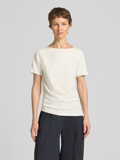 Modelka nosi T-Shirt in asymmetrischer Form Modell 'Helle' od My Essential Wardrobe, kolor jasny, drapowania, mieszanka materiałów z wiskozą, okrągły dekolt, długość tyłu 60 cm w rozmiarze S, krój regular fit, zdjęcie w pełnej sylwetce z przodu.