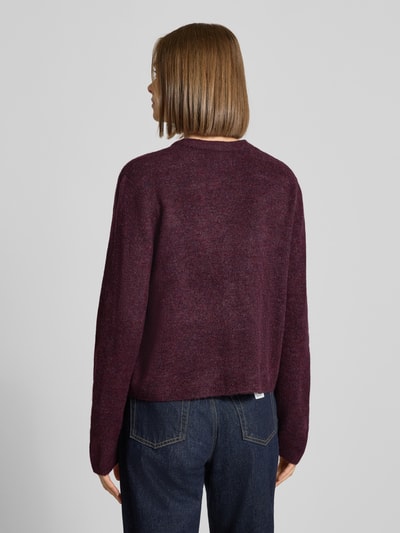 Frauenmodel trägt Loose Fit Strickjacke mit Rundhalsausschnitt Modell 'SIMONI' von ONLY in Dunkel-Lila, strukturierte Oberfläche, Ganzkörperansicht Rückansicht, Damen Strickjacke von ONLY.