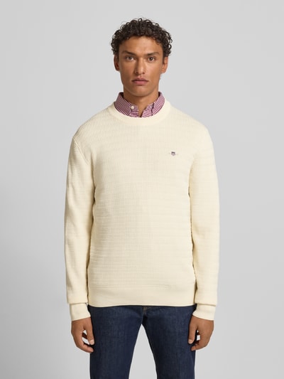 Männermodel trägt Strickpullover mit Strukturmuster und Label-Stitching von Gant, Reine Baumwolle, Regular-Fit, Rundhalsausschnitt, Creme, Ganzkörperansicht von vorne.