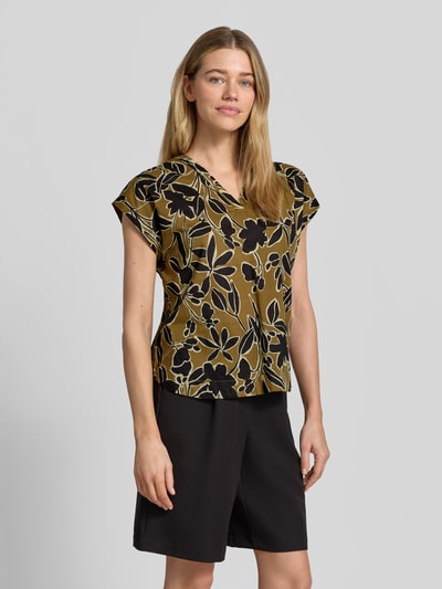 Frauenmodel trägt Blusenshirt mit V-Ausschnitt Modell 'FEODORA' von Soyaconcept, Reine Baumwolle, Gerader-Schnitt, Kappärmel, florales Muster in Oliv, Schwarz und Beige, Nahaufnahme Oberkörper.