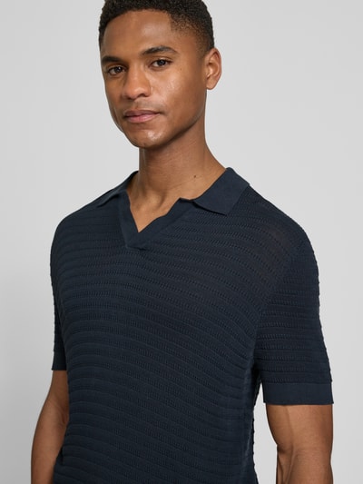Männermodel trägt dunkelblaues Slim Fit Strick-Poloshirt mit Strukturmuster, V-Ausschnitt, reine Baumwolle, Modell 'BRAIAN' von Drykorn, Nahaufnahme Oberkörper.