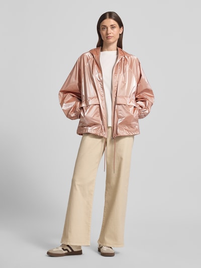 Vrouwenmodel draagt Jacke im Metallic-Look met pattentaschen van Jake*s Casual, regular fit, metallic rosé, kap met trekkoord, klepzakken, rits, ruglengte 28 cm, schouderbreedte 18 cm, borstwijdte 24 cm, mouwlengte 24 cm, vooraanzicht volledige lichaamsopname.