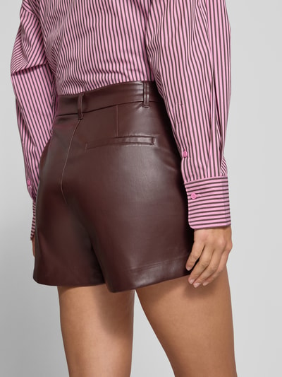 Vrouwenmodel draagt Shorts mit Bundfalten in Lederoptik van ONLY, unilook, lederlook, donkerbruin, detailopname rugaanzicht
