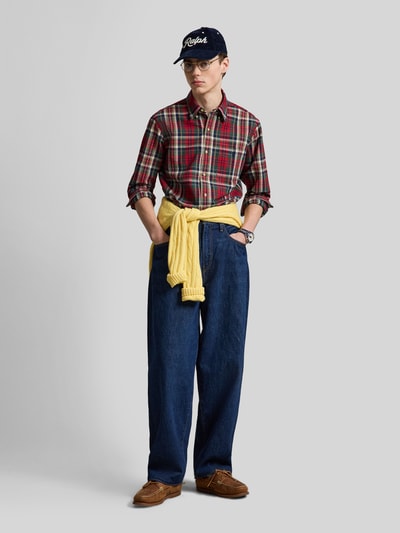 Männermodel trägt Custom Fit Freizeithemd aus reiner Baumwolle von Polo Ralph Lauren mit Karomuster in Rot und Blau, Ganzkörperansicht von vorne.